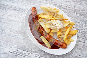 Currywurst, popular fast food in Germany consisting of sausage with curry ketchup, served with French fries and mayonnaise on an