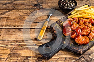 Currywurst Sausages street food served French fries on a wooden board. wooden background. Top view. Copy space