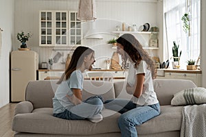 Cursing nervous woman and teenage girl are sits on couch and shouting out loud expressing resentment