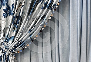 Curtain with a blue floral pattern and multi-colored pompons on the edge photo