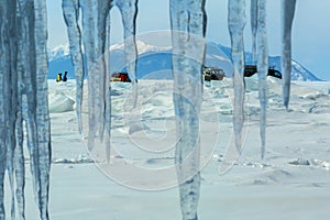 Curtain of icicles and tourist expedition on Baikal ice.