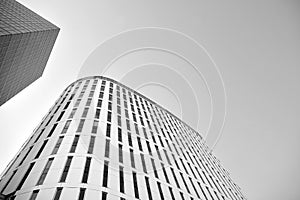 Curtain wall made of toned glass and steel constructions under sky. A fragment of a building. Black and white.