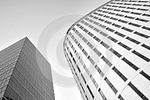 Curtain wall made of toned glass and steel constructions under sky. A fragment of a building. Black and white.