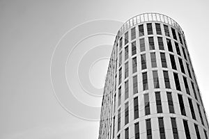 Curtain wall made of toned glass and steel constructions under sky. A fragment of a building. Black and white.