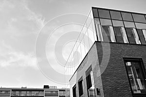 Curtain wall made of toned glass and steel constructions under sky. A fragment of a building. Black and white.