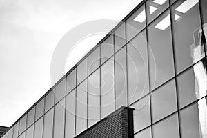 Curtain wall made of toned glass and steel constructions under sky. A fragment of a building. Black and white.