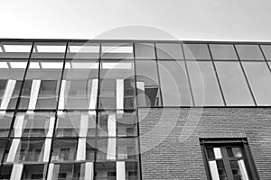 Curtain wall made of toned glass and steel constructions under sky. A fragment of a building. Black and white.