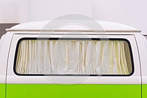 Curtained window of a bright white and green travel van