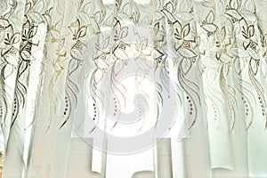 Curtains with a pattern in the hall illuminated by sunshine