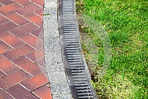 Curve iron gutter with grate to the drainage system on the side of the walkway.