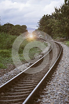The curve of railway near train station with tree at left and right side of railway,vintage filtered image,