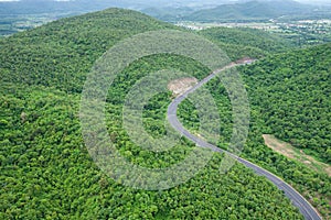 Curve road from above, road with cars through green forest and m