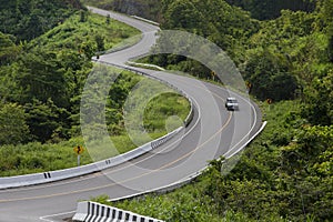 Curved asphalt road with a car in the mountains