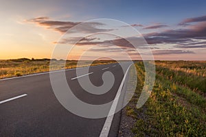 Curved asphalt road in plain at idyllic sunset