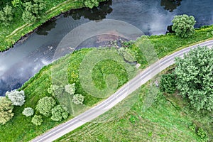 Curved bike lane pass through green meadow near river. aerial view