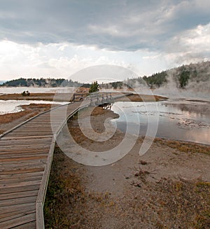 Curved Elevated wooden boardwalk going past Black Warrior Hot Springs and Tangled Creek into Hot Lake in Yellowstone National Park