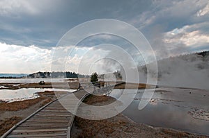 Curved Elevated wooden boardwalk going past Black Warrior Hot Springs and Tangled Creek into Hot Lake in Yellowstone National Park