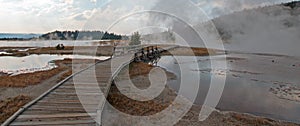 Curved Elevated wooden boardwalk going past Black Warrior Hot Springs and Tangled Creek into Hot Lake in Yellowstone National Park