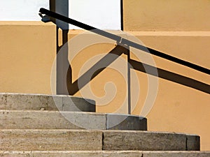 curved exterior concrete stair closeup. risers and treads. exterior wall with attached metal handrail