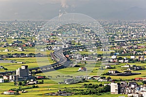 A curved highway through the green rice fields with houses scattered throughout the plain in Yilan, Taiwan