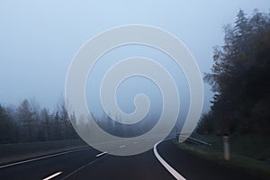 Curved higway landscape with fog and forest on sides