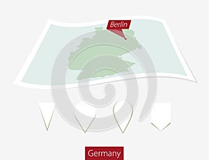 Curved paper map of Germany with capital Berlin on Gray Background. Four different Map pin set.