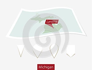 Curved paper map of Michigan state with capital Lansing on Gray