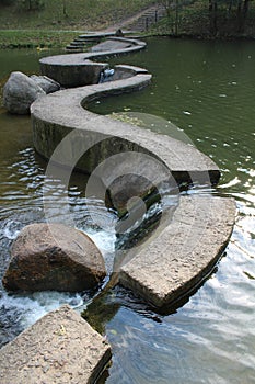 Curved path and stones in the middle of the river. Japanese landscape style