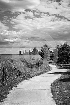 A curved path with vegetation and trees on either side leading towards a view of the Chicago skyline with highrise buildings and