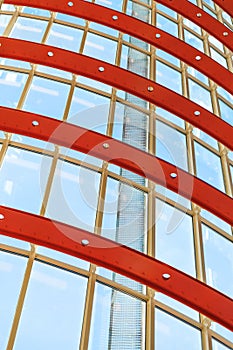 Curved red and white metal structures hold the window systems. Through the glass passes bright sunlight. Illustration of the