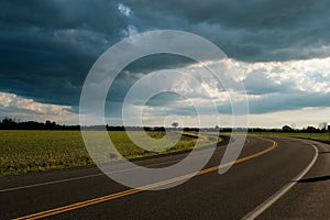 Curved road with dramatic summer storm clouds