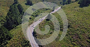 Curved road surrounded by forest green trees cars