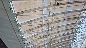 Curved roof with windows of a large shopping center indoors. Modern metal and glass ceiling construction