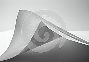 Curved sheets of white paper create a dynamic, flowing visual effect. The interplay of
