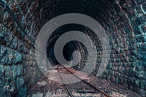 Curved stone railway tunnel with railroad tracks