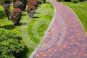 Curved stone tile pavement curved path in park landscaped.