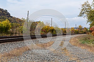 Curved train tracks running through a rural area, fall landscape with autumn leaves