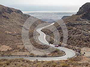 Curved winding road with a red car in the mountains in Gran Canaria