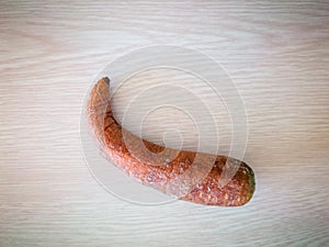 Curved withered carrot isolated on wood texture background, shrivel inedible overripe vegetable, food decay concept