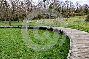 Curved wooden elevated walkway bridge on green grass