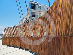 Curved wooden fence with warning signs blocking off dangerous wires