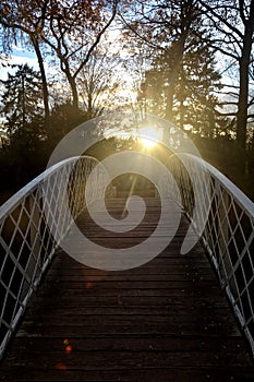 Curves bridge of wood with white metal area and autumnal trees and with sundown