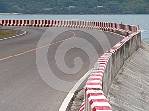 Curves on the road by the sea and the red stripe warns drivers.
