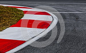 Curving asphalt red and white kerb of a race track detail