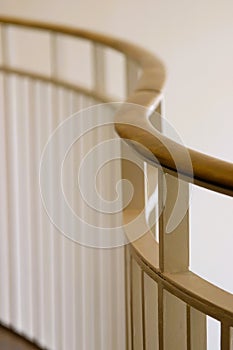 Curving brass railing on white metal pickets against white wall