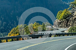 Curving country road surrounded by forest, rock and autumn colored foliage