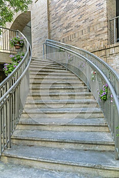 Curving outdoor stairway with steel rails decorated with hanging flower plants