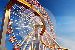 A curving rail cuts in front of a large Ferris wheel