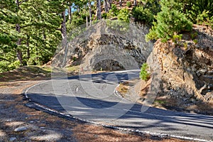 Curving road or street along a steep mountain valley. Winding pathway with sharp curve going up the hill with trees on