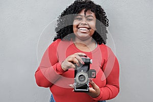 Curvy african woman using vintage camera outdoor - Focus on face